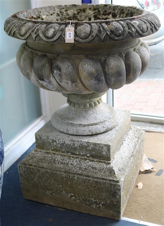 A pair of reconstituted stone garden urns, of campana shape, raised on stepped plinths